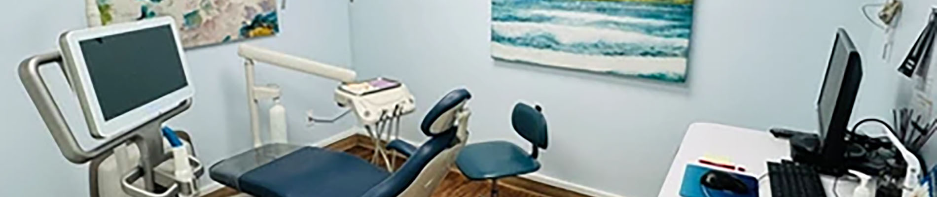 The image shows an interior view of a dental office, with a dental chair in the foreground and various dental equipment visible.