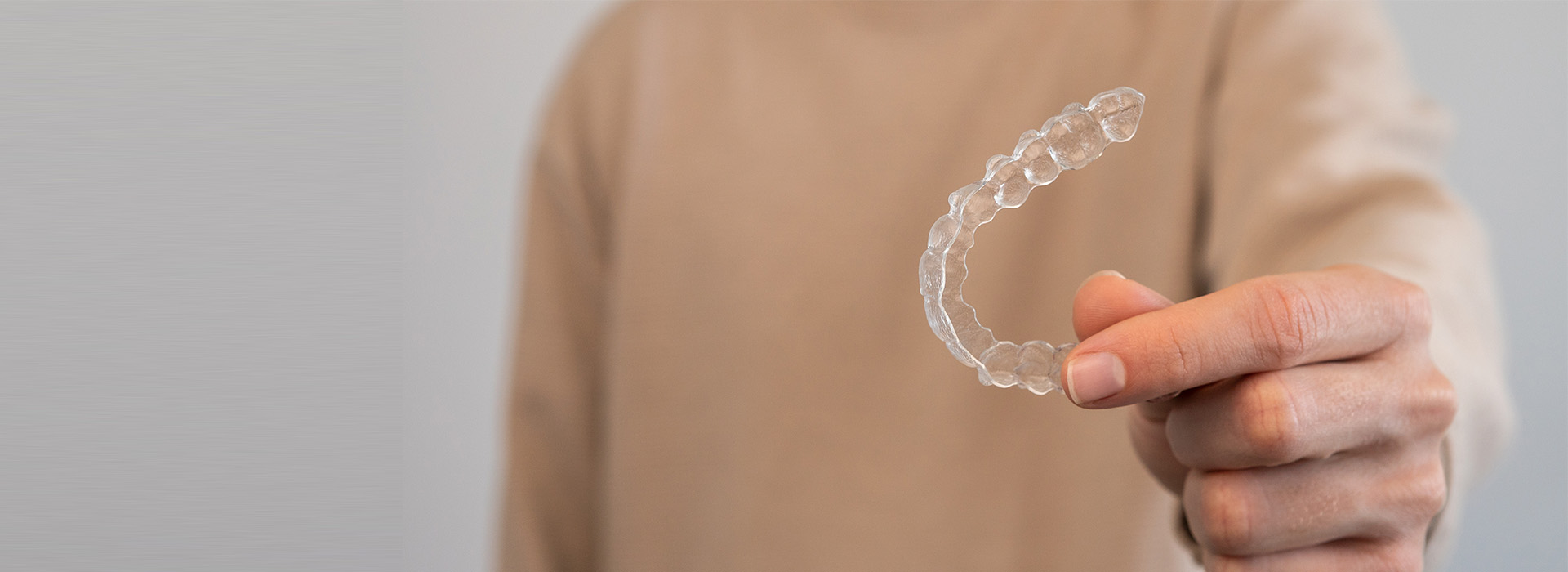 The image shows a person s hand holding a small, clear plastic bubble against a blurred background.