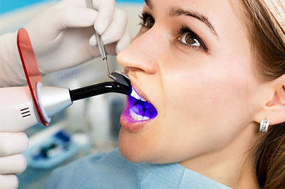 A dental hygienist is using a device to clean a patient s teeth.