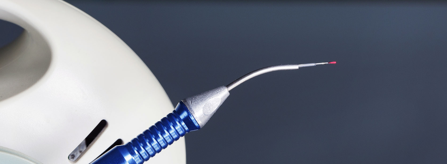 The image features a close-up of a medical device, specifically an endoscopic tool with a needle attached to it, against a blurred background that appears to be a clinical or hospital setting.